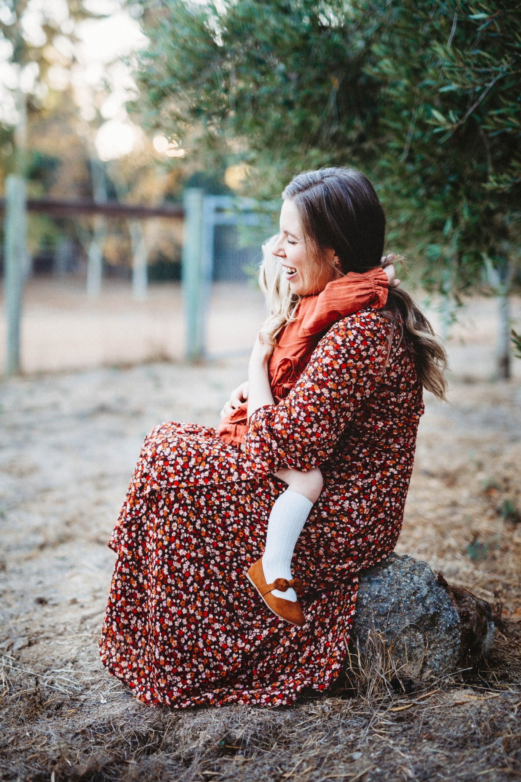 Emily Keegan sitting outdoors, hugging her daughter during a quiet moment