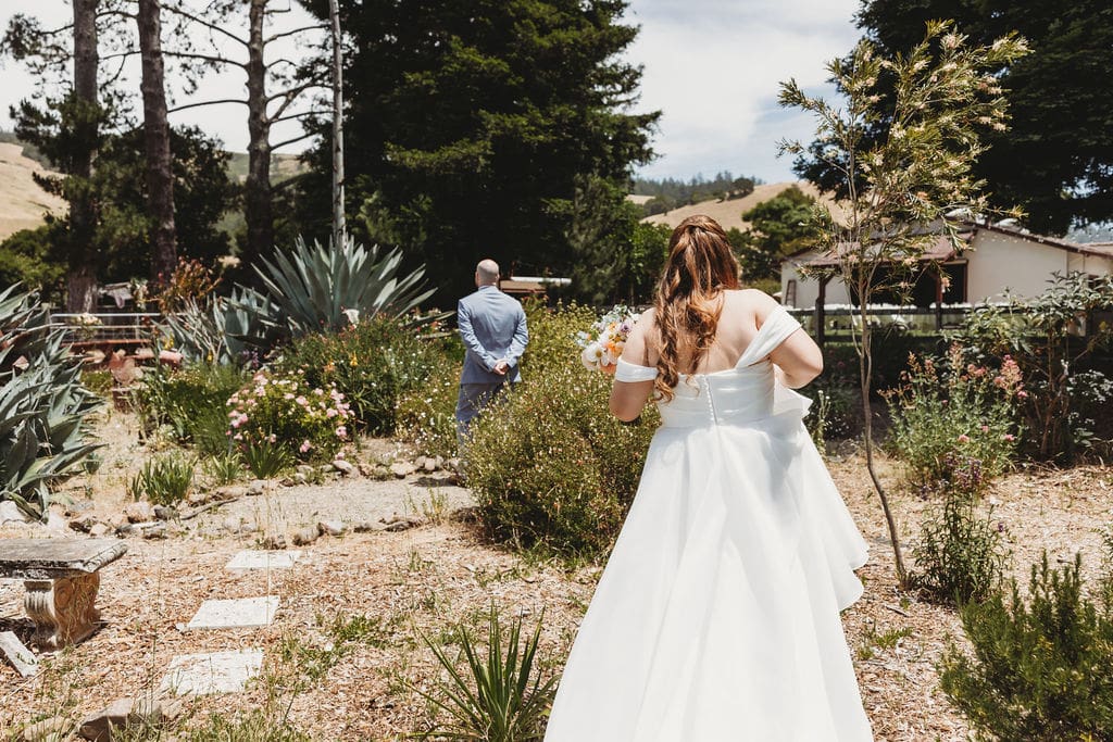 Bride and groom walking away together down a garden walkway at Rancho Nicasio wedding