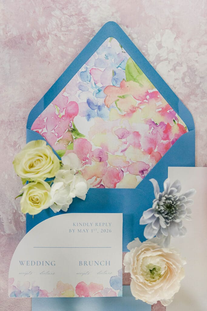 Watercolor wedding RSVP cards and blue envelope flat lay